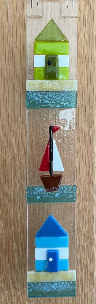 Light catcher showing beach huts and yacht.