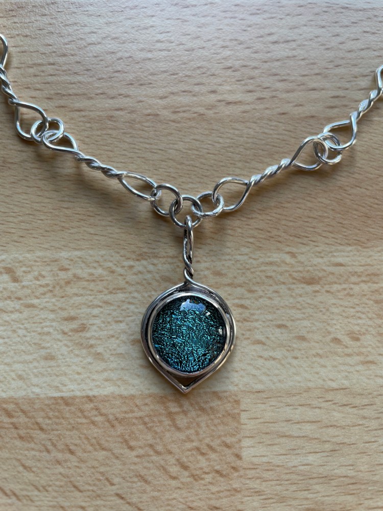 Pendant made from a fused glass, cabochon and hand made silver wire necklace. The bezel is made from silver with a silver back. The clasp is made from the same silver wire as the necklace.