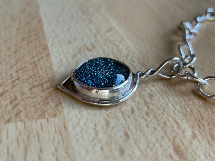 Pendant made from a fused glass, cabochon and hand made silver wire necklace. The bezel is made from silver with a silver back. The clasp is made from the same silver wire as the necklace.