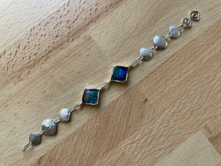 Bracelet using fused glass cabochons set in sterling silver bezels and using reticulation on sheet silver.