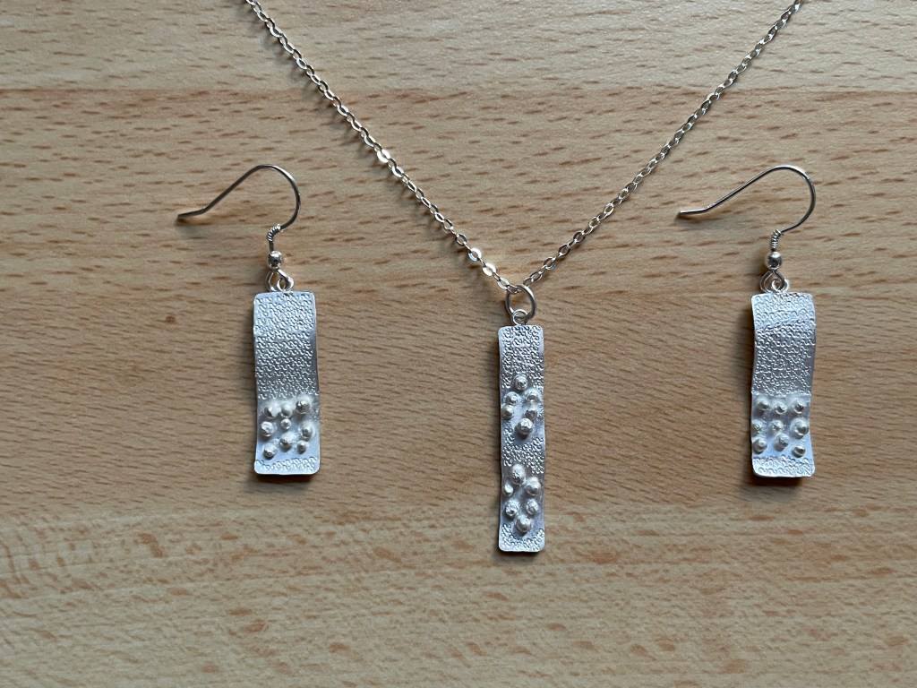 Pendant and earring set using granulation and punching.
