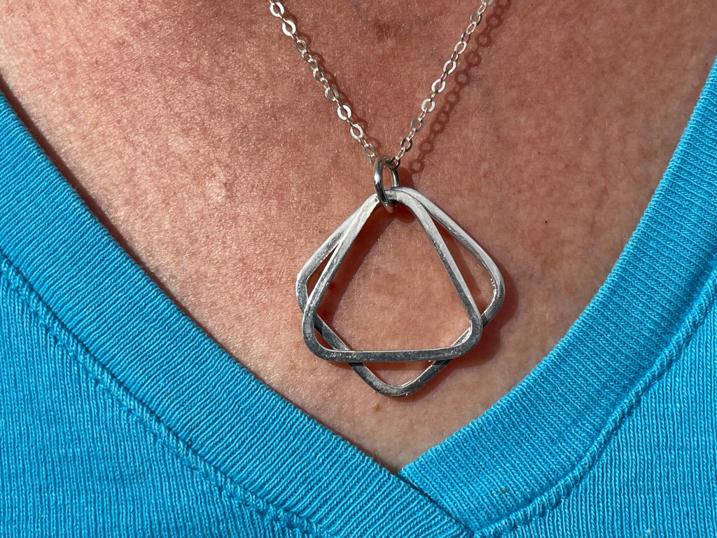 Silver pendant using square wire to make two shapes which hand loosely from a jump ring allowing them to move freely.